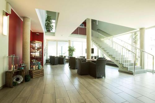 a lobby with chairs and a staircase in a building at Atlantic Hotel am Floetenkiel in Bremerhaven