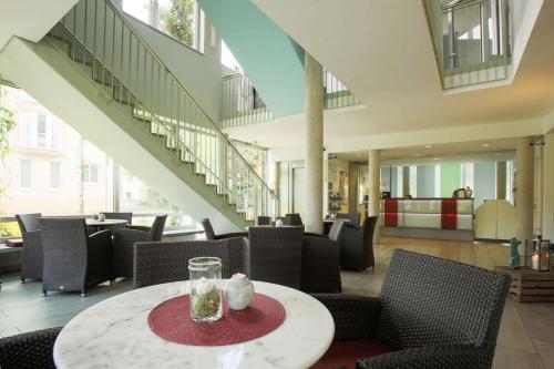 a restaurant with a table and chairs and stairs at Atlantic Hotel am Floetenkiel in Bremerhaven