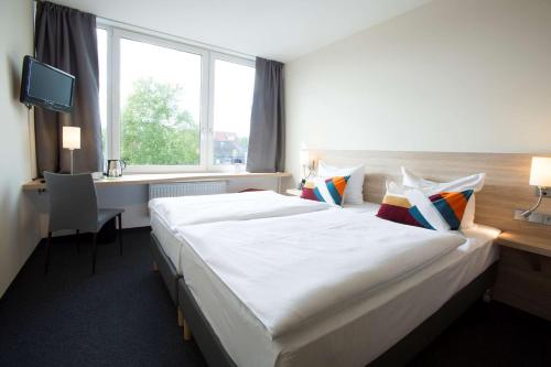 Habitación de hotel con cama grande y escritorio. en Atlantic Hotel am Floetenkiel, en Bremerhaven