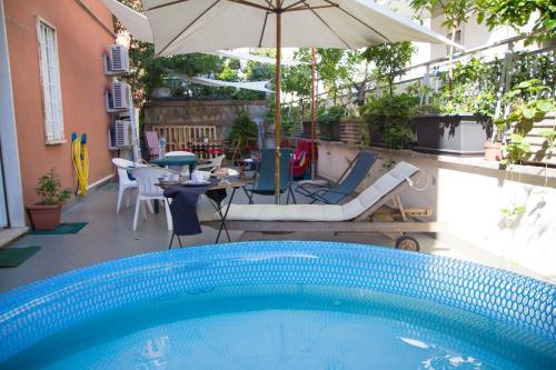 uma piscina com um guarda-sol, uma mesa e cadeiras em Bausan 12 em Roma