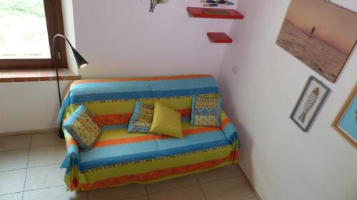 a couch with colorful pillows sitting in a room at I Pesci nel golfo di Baratti in Baratti