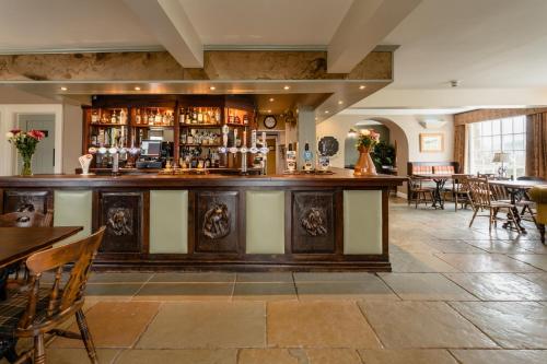 a bar in a restaurant with tables and chairs at The Percy Arms in Chatton