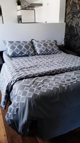 - un lit avec une couette et des oreillers bleus dans l'établissement Studio chaleureux en hyper centre, à Charleville-Mézières