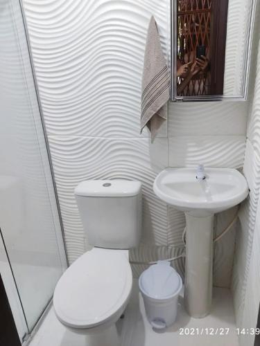 a white bathroom with a toilet and a sink at Pousada Carpediem in Morro de São Paulo