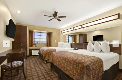 a hotel room with two beds and a ceiling fan at Microtel Inn & Suites by Wyndham Round Rock in Round Rock