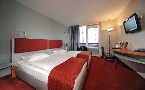 ein Hotelzimmer mit einem Bett, einem Schreibtisch und einem TV in der Unterkunft Nordsee Hotel Fischereihafen in Bremerhaven