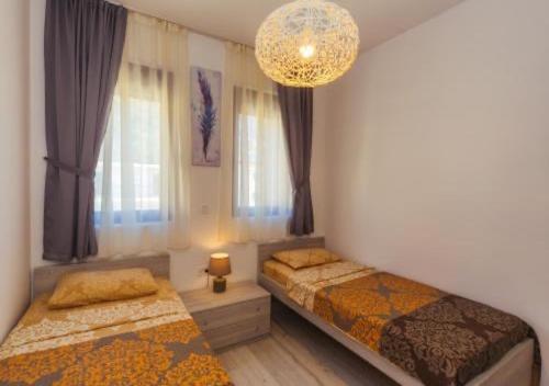 a bedroom with two beds and a chandelier at Engora 5 in Petrovac na Moru