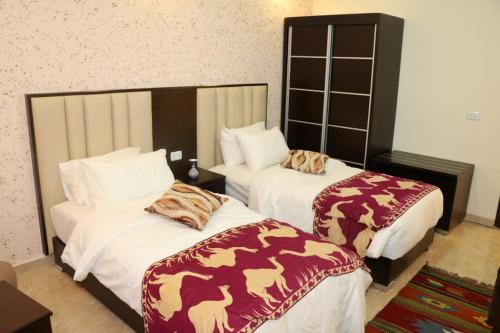 een hotelkamer met twee bedden met dekens erop bij Petra Stones Inn in Wadi Musa