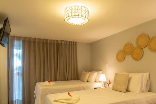 a hotel room with two beds and a chandelier at Tropical Beach in Porto Seguro