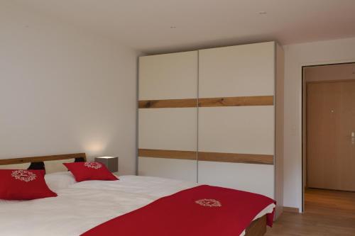 a bedroom with a large bed with red pillows at Apartment Olympia Matterhorn in Zermatt