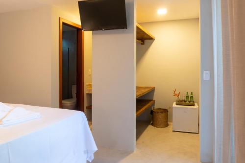 a bedroom with a bed and a tv on a wall at Tropical Beach in Porto Seguro