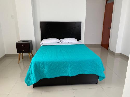 a bedroom with a large bed with a blue blanket at Hotel Munay in Paracas