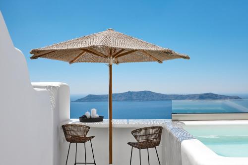 eine Terrasse mit einem Tisch, Stühlen und einem Sonnenschirm in der Unterkunft U & ME SUITES in Fira