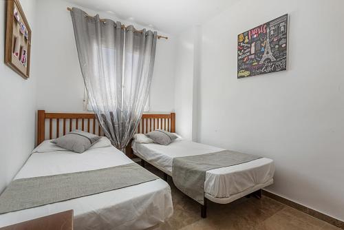 2 camas individuais num quarto com uma janela em urbanización Catamaran em Denia