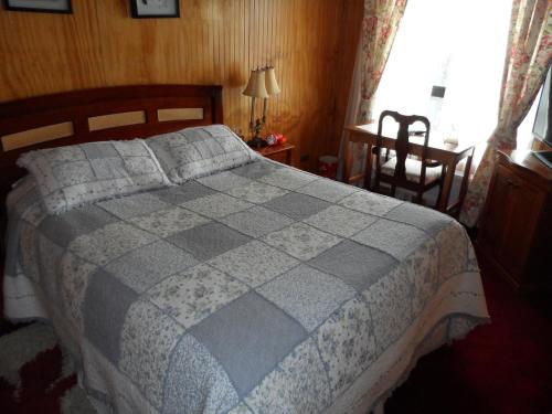 a bedroom with a bed and a chair and a window at Hostal Español Coyhaique in Coihaique