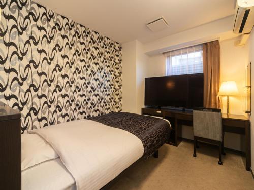 um quarto com uma cama, uma secretária e uma televisão em APA Hotel Osaka-Kadomashi Ekimae em Osaka