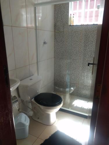 uma casa de banho com um WC e uma cabina de duche em vidro. em Doce Lar em Cabo Frio