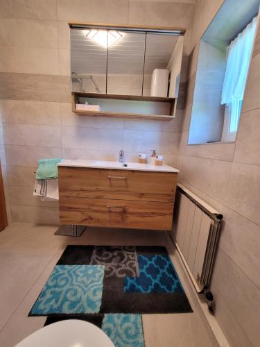 een badkamer met een wastafel, een spiegel en een tapijt bij Ferienwohnung Anna in Grödig