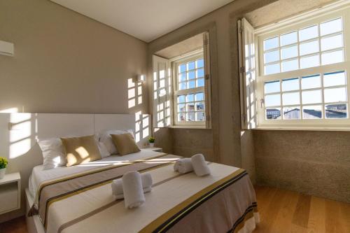 a bedroom with two beds and two windows at Portucale Guest House- Self check-in in Porto