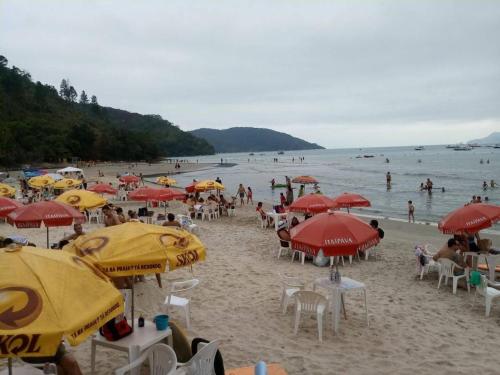 a group of people sitting on a beach with umbrellas at Excellence Apart in Ubatuba
