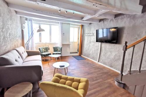 un salon avec un canapé et une télévision sur un mur dans l'établissement Splendide Maison 5 chambres ! Quartier Historique, à Limoges