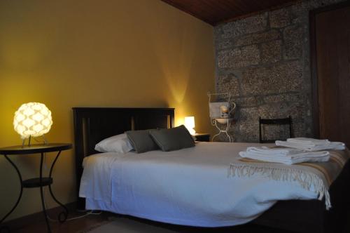 1 dormitorio con cama blanca y pared de piedra en Casa dos Antunes en Terras de Bouro