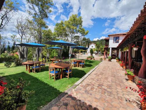 a patio with tables and chairs with umbrellas at Hacienda Buenos Aires en Iza in Iza