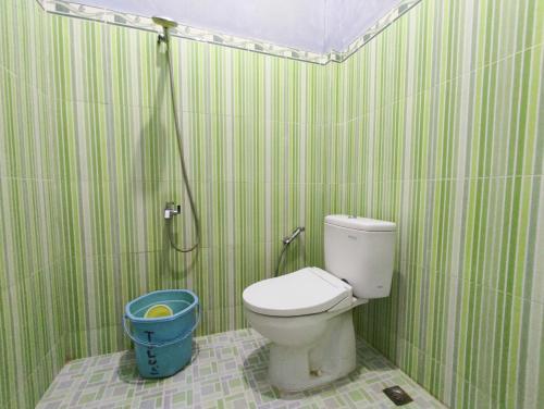 a green and white bathroom with a toilet and a shower at Wisma Tulus Syariah Kebumen Mitra RedDoorz in Kebumen