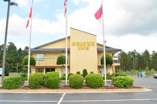 a building with flags in front of a parking lot at Deluxe Inn - Fayetteville I-95 in Fayetteville