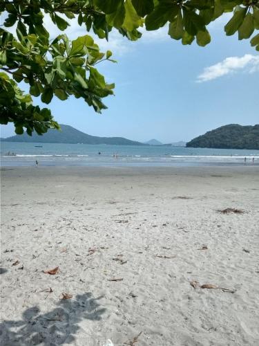 a beach with people walking in the water at Casa pé na areia in Ubatuba