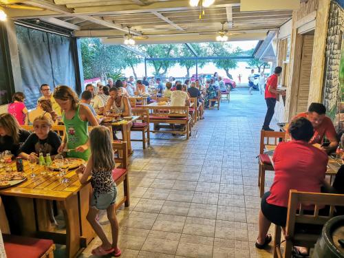 un grupo de personas sentadas en mesas en un restaurante en Pansion Karoca, en Vodice
