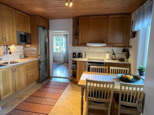 a kitchen with wooden cabinets and a table and chairs at Naturskönt boende nära Skövde in Skövde