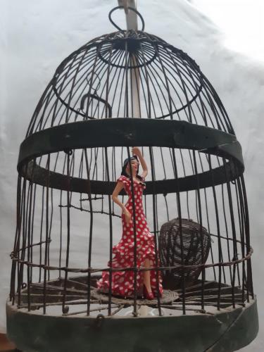 a woman is standing inside of a bird cage at La Posada Amena in Carcabuey