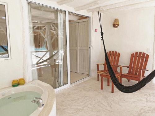a hammock in a room with a tub and two chairs at Coco Unlimited in Tulum
