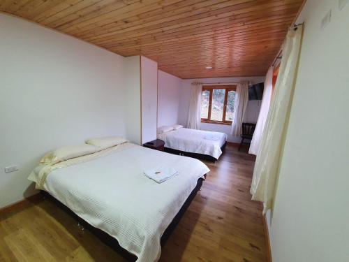 a bedroom with two beds and a wooden ceiling at Hacienda Buenos Aires en Iza in Iza
