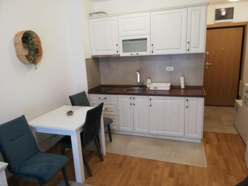 a kitchen with white cabinets and a table and chairs at Vila Irina Kopaonik in Kopaonik
