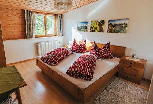 a bedroom with a bed with red and white pillows at Gästezimmer & Buschenschank mit Weingut Hack-Gebell in Gamlitz