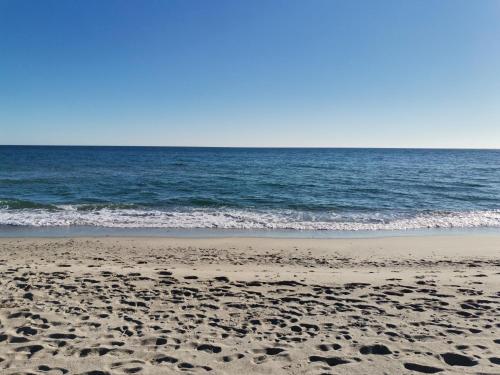a beach with footprints in the sand and the ocean at Le Zagare Case Vacanza in Cropani