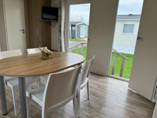 a dining room table and chairs with a view of a porch at Moderne stacaravan in Middelkerke
