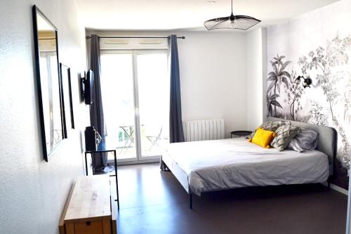 um quarto com uma cama e uma grande janela em Studio Cosy Bordeaux - Parking privé - Netflix - Tram A em Cenon