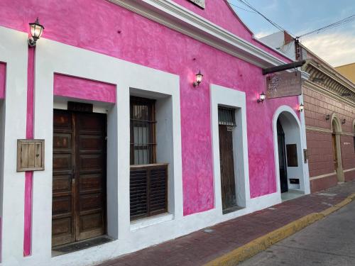 a pink and white building with two brown doors at Villa Serena Centro Historico in Mazatlán