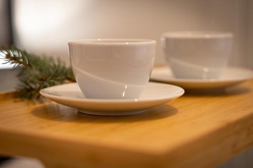 two white cups and saucers on a wooden table at Chata Stylchyn in Kluszkowce