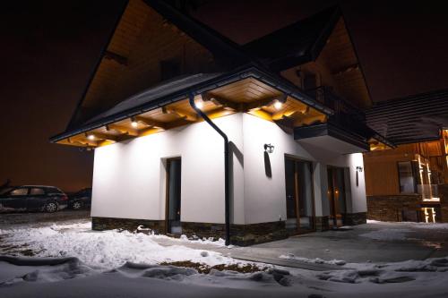 a lit up building in the snow at night at Chata Stylchyn in Kluszkowce