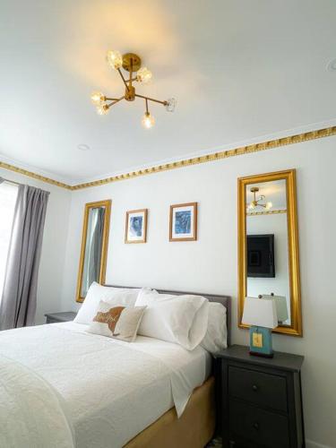 a bedroom with a white bed with a mirror and a lamp at Luxurious Room near LaGuardia & JFK in Corona
