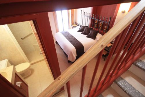 a bedroom with a bed and a staircase with a mirror at Hotel Santa Regina in Guanajuato