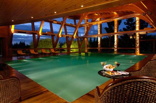 a swimming pool with a table and chairs in it at Hotel Posada Los Alamos in El Calafate