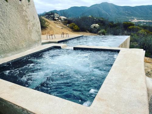 a plunge pool with chairs and mountains in the background at Casa Misiones Glamping in Valle de Guadalupe