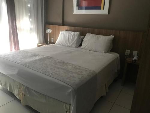 1 dormitorio con 1 cama grande con sábanas blancas y almohadas en RIOSTAY Riocentro Apart-Hotel, en Río de Janeiro