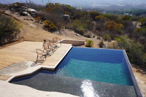 a swimming pool with two chairs and a wooden deck at Casa Misiones Glamping in Valle de Guadalupe