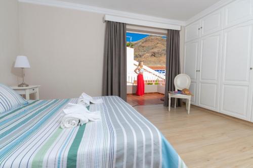 1 dormitorio con 1 cama con una mujer en la ventana en Villa Santiago, en La Playa de Tauro